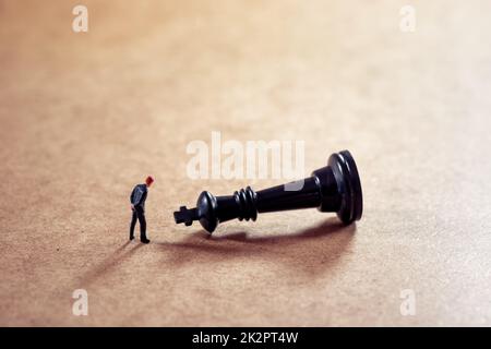 Ein nachdenklicher Geschäftsmann, der Schachfiguren ansieht Stockfoto