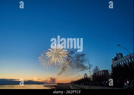 Buntes Feuerwerk auf dem Hintergrund des Himmels am Flussufer Stockfoto