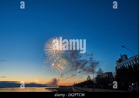 Buntes Feuerwerk auf dem Hintergrund des Himmels am Flussufer Stockfoto