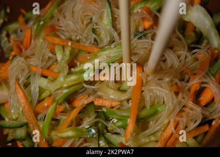 Funchoza-Salat mit Gemüse auf schwarzem Hintergrund, Draufsicht. Glasnudeln, asiatisches Essen. Vegetarisches Essen gesund Stockfoto