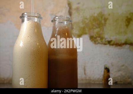 Milchshake-Schokoladenmilch in Flaschen mit Pailletten Vintage Hintergrund Closu-up-Ansicht Stockfoto