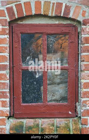 Ihr Blick auf die Welt. Nahaufnahme eines rustikalen Fensterrahmens auf einem Backsteinhaus. Stockfoto