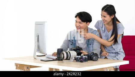 Asiatischer Fotograf und Modell, der sich Bilder ansieht, die auf dem Computermonitor aufgenommen wurden. Das junge Model ist sehr zufrieden mit ihrem Foto. Die Atmosphäre im Fotostudio. Stockfoto