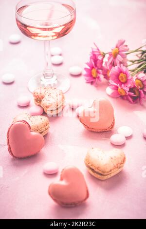 Happy Mothers Day - süße Macarons und ein Glas Rosé-Sekt mit Blumen in rosa Ton Stockfoto