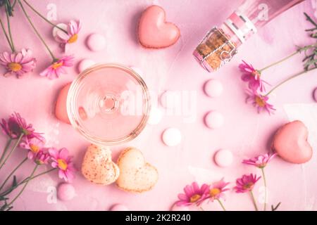 Happy Mothers Day - süße Macarons und ein Glas Rosé-Sekt mit Blumen in rosa Ton Stockfoto