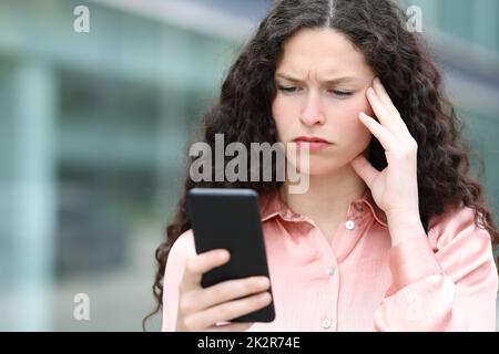 Eine besorgte Frau liest auf der Straße am Telefon Nachrichten Stockfoto