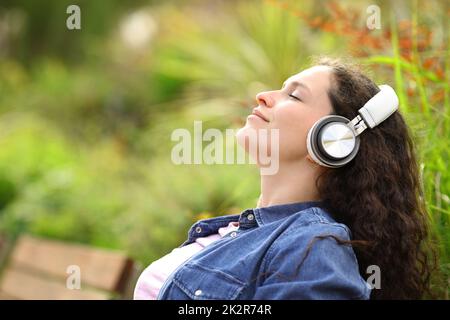 Eine Frau, die sich entspannt und in einem Park Musik hört Stockfoto