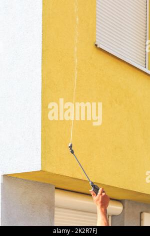 Aufbringen von Reinigungsmitteln auf schmutzige Fassade mit Hochdruckwasserstrahl Stockfoto