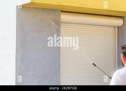 Aufbringen von Reinigungsmitteln auf schmutzige Fassade mit Hochdruckwasserstrahl Stockfoto