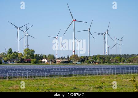 Solarpaneele mit Windrädern im Rücken in Deutschland gesehen Stockfoto