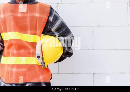 Rückansicht des Technikers, Architekten, Vorgesetzten tragen reflektierende Kleidung zur Sicherheit der Arbeit Halten Sie den Schutzhelm Stockfoto