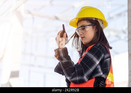 Asiatischer Ingenieur Vorarbeiter Architekt Arbeiter Frau auf Baustelle im Gespräch mit Radio, Engineering halten Radio zu diskutieren bedienen und zu kontra Stockfoto