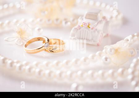 Hochzeit Stillleben mit goldenen Ringen und Perlenkette in weiß Stockfoto