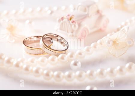 Hochzeit Stillleben mit goldenen Ringen und Perlenkette in weiß Stockfoto