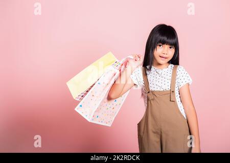 Asiatisches kleines Kind 10 Jahre alt lächelnd mit bunten Einkaufstaschen in den Händen Stockfoto