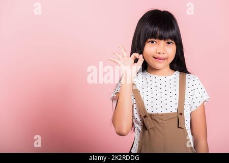 Asiatisches kleines Kind im Alter von 10 Jahren, das eine gute Geste in Gebärdensprache zeigt Stockfoto