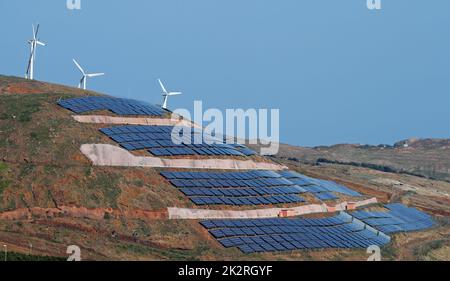 Photovoltaik-Sonnenkollektoren und Windturbinen, die Strom auf einem Hügel und blauem Himmel erzeugen. Ökologie grün Natur Konzept. Stockfoto