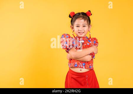 Glücklich asiatische chinesische kleine Mädchen lächeln tragen rote Cheongsam gekreuzte Arme Stockfoto