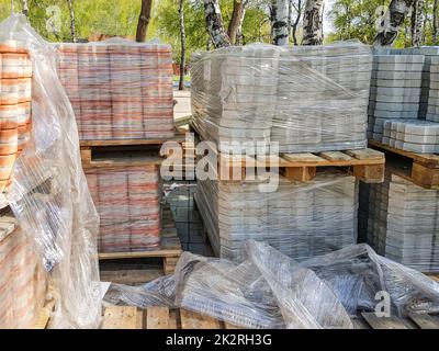 Nahaufnahme: Die neuen Pflasterplatten werden übersichtlich auf Paletten gestapelt. Reparatur von Gehwegen und Ersatz von Pflasterplatten. Wiederaufbau der städtischen Infrastruktur Stockfoto