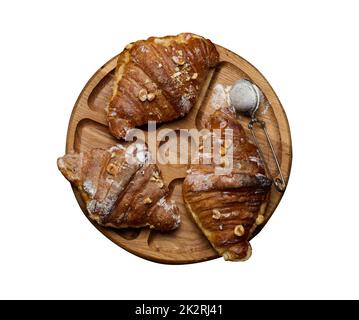 Gebackene Croissants auf einem Holzbrett und mit Puderzucker bestreut Stockfoto