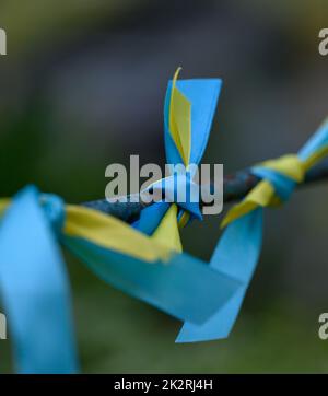 Blaues und gelbes Seidenband an einem Metallrohr gebunden. Ukrainisches Flaggensymbol, Kampf um Unabhängigkeit Stockfoto