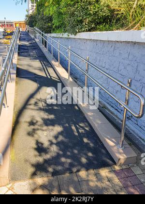 Moderne Rampe mit glänzenden Metallgeländern im Freien, rollstuhlgerecht, Nahaufnahme, vertikal Stockfoto