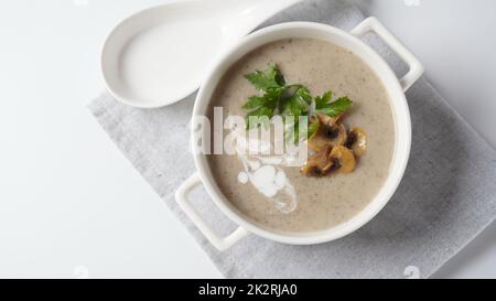 Pilzsahnesuppe mit gebratenen Champignons und frischer Petersilie. Konzept für heiße Suppe im Winter und Herbst Stockfoto