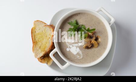 Pilzsahnesuppe mit gebratenen Champignons und frischer Petersilie. Konzept für heiße Suppe im Winter und Herbst Stockfoto