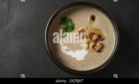 Pilzsahnesuppe mit gebratenen Champignons und frischer Petersilie. Konzept für heiße Suppe im Winter und Herbst Stockfoto