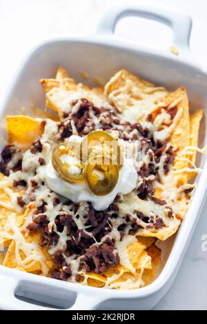 Nachos mit Rinderhackfleisch und Käse, serviert mit Schlagsahne und Jalapenos Stockfoto