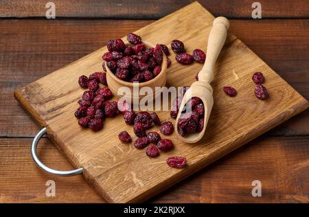 Ein paar getrocknete Preiselbeeren in einem Holzlöffel auf einem braunen Tisch. Köstliche Beeren, Blick von oben Stockfoto