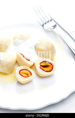 Pflaumenknödel mit Sauerrahm, Puderzucker und geschmolzener Butter Stockfoto