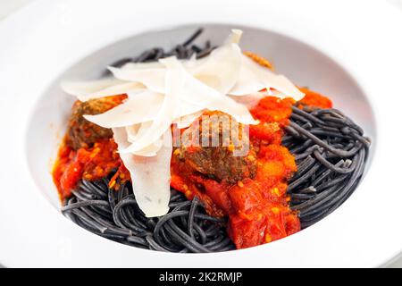 Schwarze Spaghetti mit Tomatensauce und Fleischbällchen Stockfoto