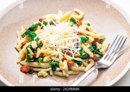 Spetzel mit Spincha-Blättern, geräuchertem Speck und geriebenem Käse Stockfoto