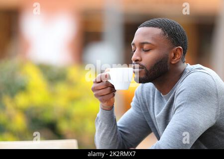 Mann mit schwarzer Haut, der das Aroma einer Kaffeetasse genießt Stockfoto