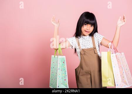 Asiatisches kleines Kind 10 Jahre alt lächelnd mit bunten Einkaufstaschen in den Händen Stockfoto