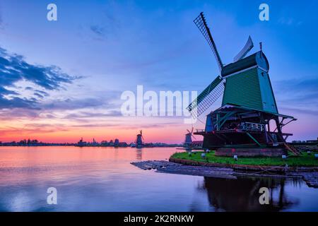 Windmühlen an der berühmten Touristenattraktion Zaanse Schans in Holland mit dramatischem Himmel. Zaandam, Niederlande Stockfoto