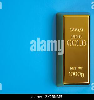 Ein Ingot aus goldenem Metallbarren von reinem Brillanz diagonal auf blauem Hintergrund. Stockfoto