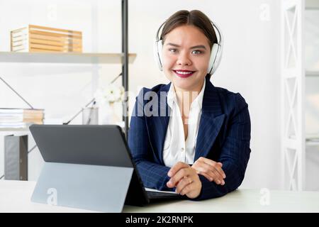 Online-Lernen. Business-Coaching. Internetkommunikation. Videokonferenz. Fröhliche erfolgreiche Frau in weißen Kopfhörern, die vom Heimbüro aus arbeitet Stockfoto