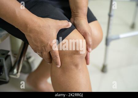 Asiatische Dame Frau Patientin berühren und fühlen Schmerzen ihr Knie, gesundes medizinisches Konzept. Stockfoto