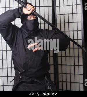 Asian man trägt Ninja Kostüm und hält Ninja Waffen Stockfoto