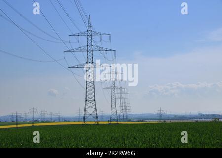 Mehrere Hochspannungsmasten gegen einen blauen Himmel Stockfoto