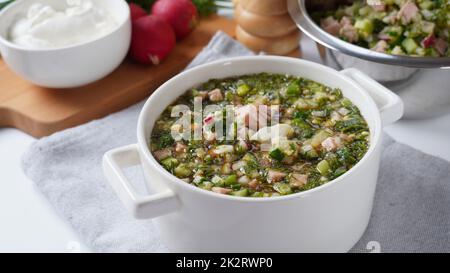 Okroshka, Sommerleichte kalte Suppe mit Gurken, Rettich, Eiern und Dill mit Sauerrahm und grünen Zwiebeln Stockfoto