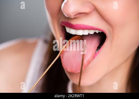 Frau Reinigung der Zunge mit Reiniger Stockfoto