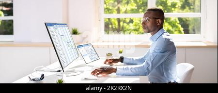 Geschäftsmann, Der An Gantt Chart Am Büroschreibtisch Arbeitet Stockfoto