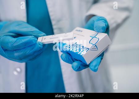 Asiatischer Arzt im PSA-Anzug mit Speichelantigen-Testkit zur Kontrolle des Covid-19-Coronavirus im Krankenhaus. Stockfoto