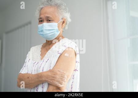 Ältere asiatische ältere Frau, die Gesichtsmaske trägt, erhält von einem Arzt eine Covid-19- oder Coronavirus-Impfung. Stockfoto