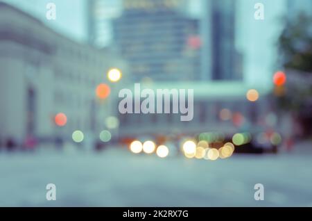Verschwommene Stadtstraße mit Verkehr, Bokeh und Gebäudehintergrund. Stockfoto