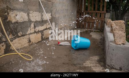 Wischen Sie mit dem auf dem Boden zurückgebliebenen, überfluteten Mopp, der mit einem Wassersprühnebel besprüht wird. Stockfoto