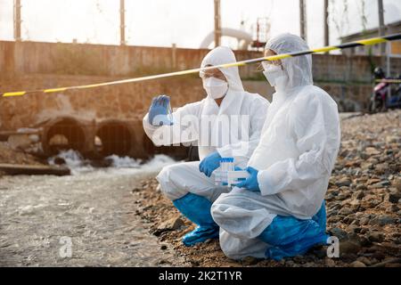 Ökologe, die Wasser aus dem Fluss mit einem Reagenzglas entnehmen Stockfoto